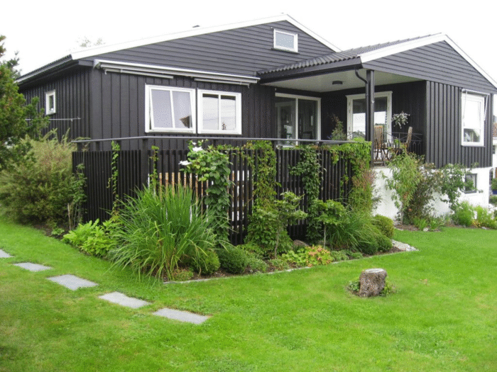 Huset sett med terrassen og blomsterbed