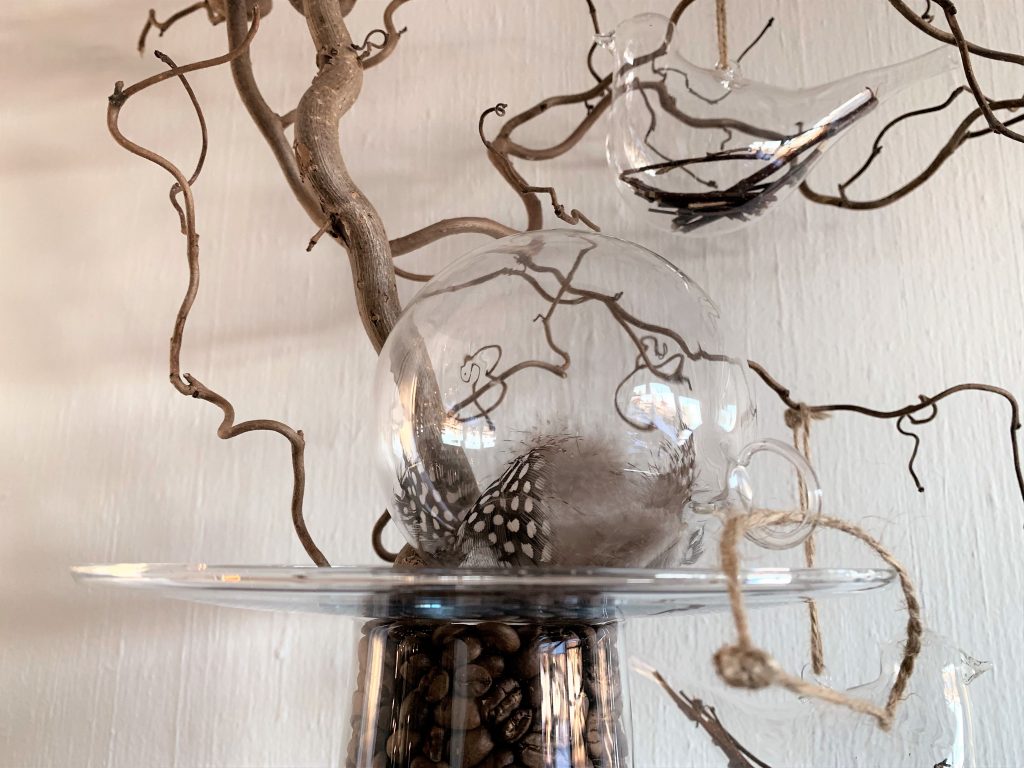 Vase med kaffebønner og vrihassel med glassfugler og kule